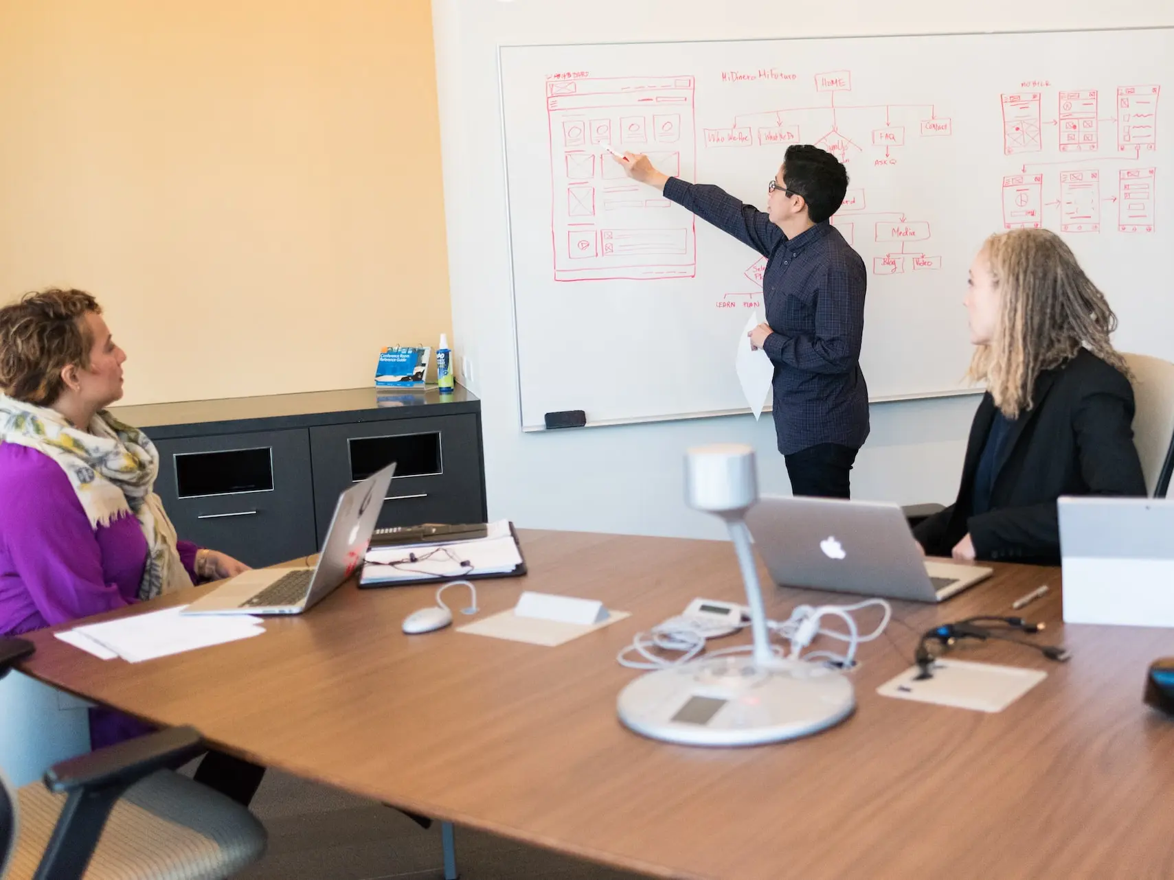 man in black dress shirt writing on dry-erase board